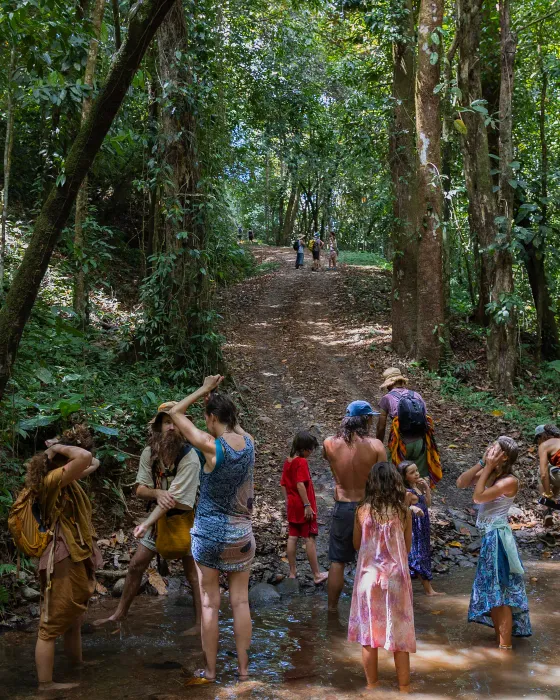Children and adults standing together in the shallow river that runs through the land at Amora, the ecovillage above Dominicalito, Costa Rica.
